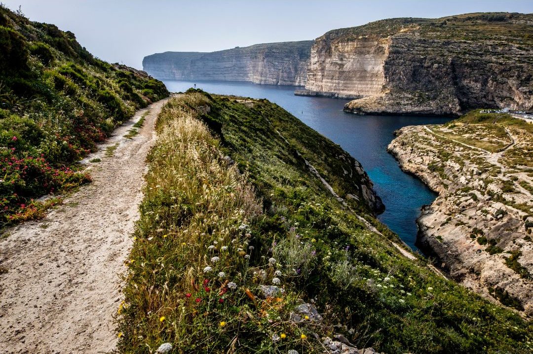 A scenic view of Xlendi Valley, with lush greenery and towering cliffs surrounding the area.