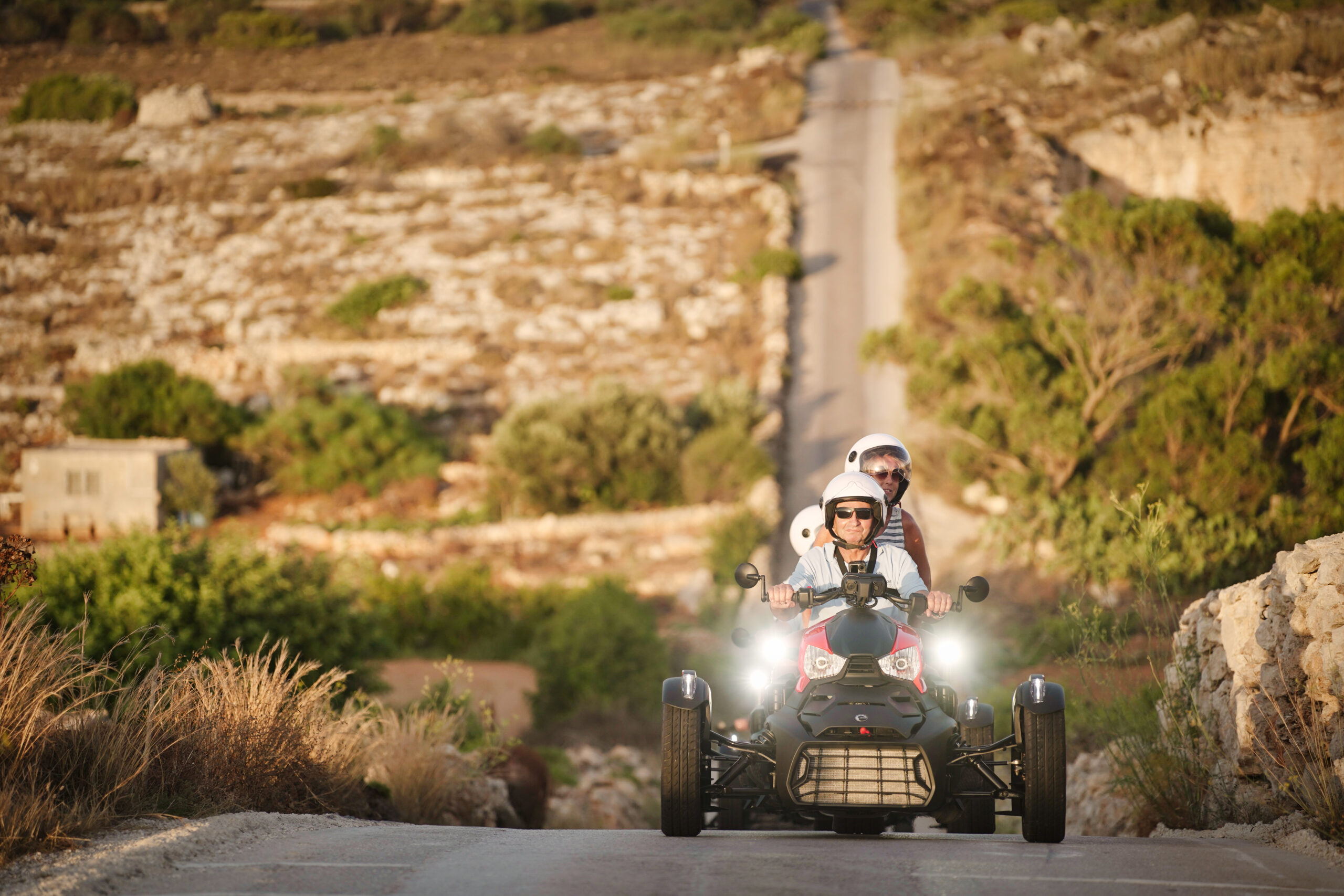 Couple riding a Ryker through the countryside, smiling and enjoying the view.
